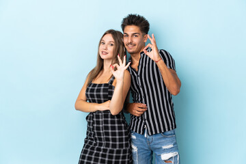 Naklejka premium Teenager caucasian couple isolated on blue background showing an ok sign with fingers