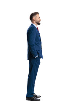 Smiling businessman standing with hands in pockets looking side