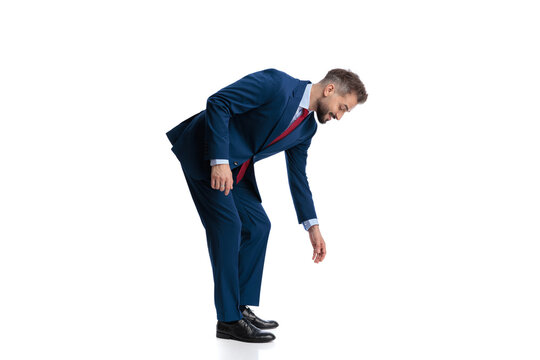 Side view of curious businessman bending and reaching down