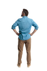 Confident man standing with hands on hips looking to side