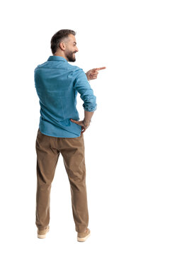 Back view of smiling casual man pointing to side