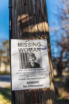 Missing woman poster with reward notice attached to wooden utility pole on suburban street in USA