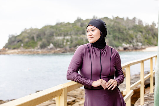 Close up of Hmong-American woman leaning on wooden railing of coastal path