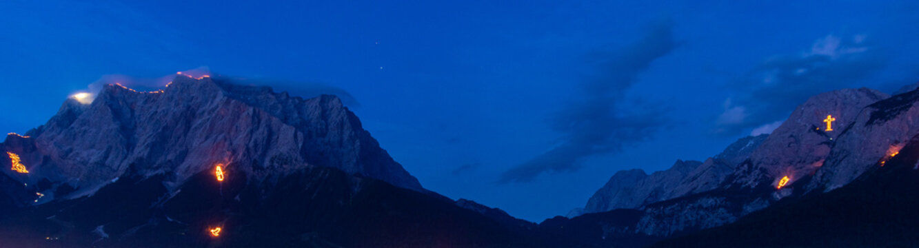Mountain peaks illuminated by traditional solstice fires in the Austrian Alps at dusk