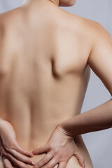 Fototapeta premium Spine osteoporosis. Backache. Scoliosis. Spinal cord problems on womans back. Beautiful naked woman touching her pain back.