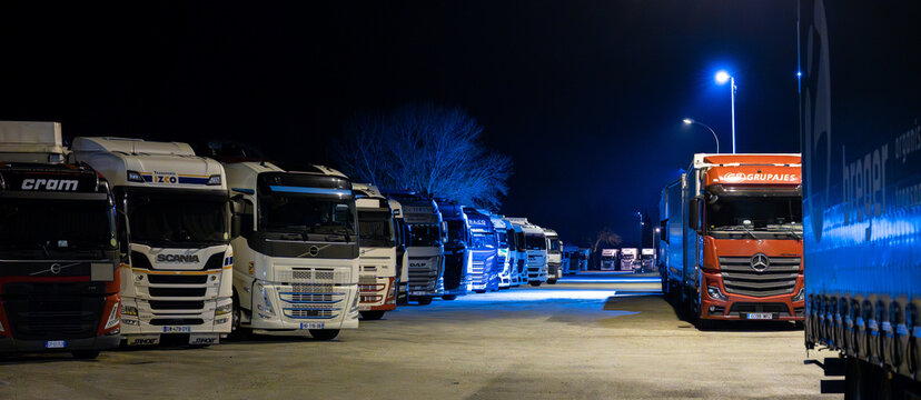 Saint-Martin-de-Crau, Arles area, France, 18 February 2026: long perspective of parked trucks under blue night lighting