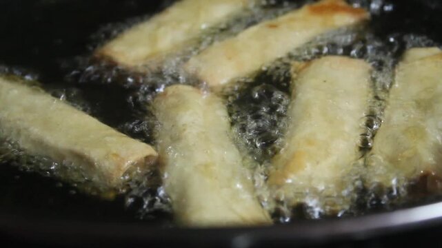 frying spring rolls in a frying pan