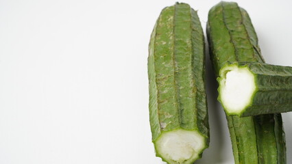 Isolated white photo of a vegetable called oyong or gambas (Luffa acutangula) which is long, has green skin and a hard texture with a white inside.