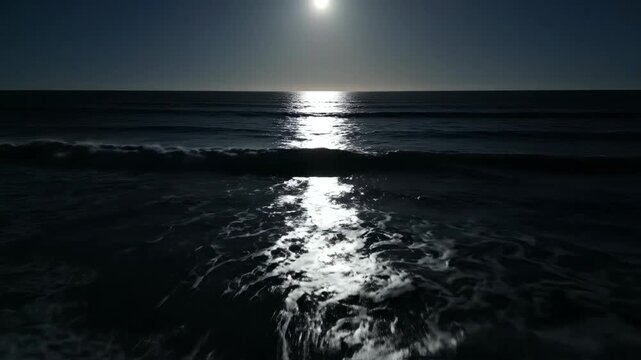 Moonlight reflecting on ocean waves at night, showcasing the gradual movement of water and shimmering light across the surface in a serene coastal setting