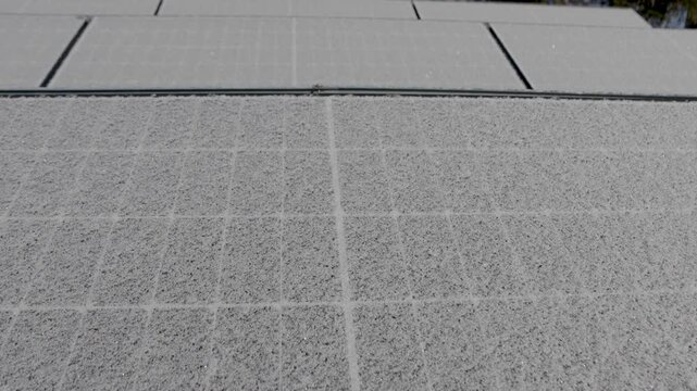 Close-up of rooftop solar panels covered in a thick layer of snow, illustrating winter conditions and their impact on renewable energy production. Shallow depth of field with blurred background