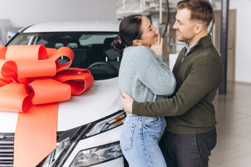 Young man hugging grateful woman receiving a new car as a surprise present, celebrating special...