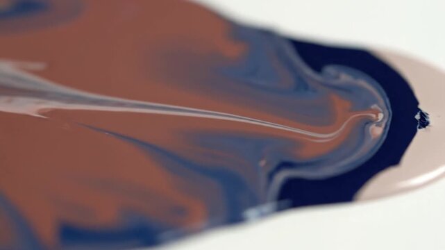 A sequence of images capturing the process of blue and white paint being mixed or poured on a white surface, creating swirling, marbled patterns with brownish hues.