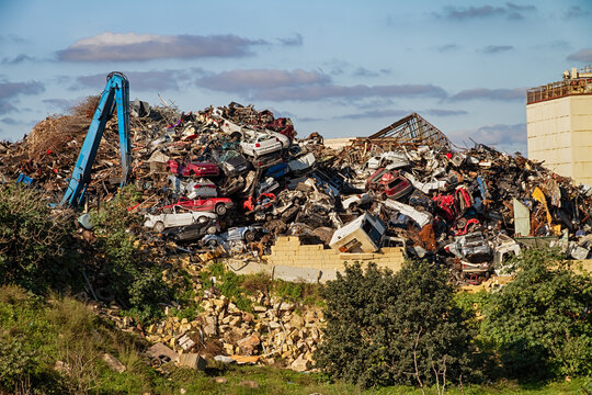 Industrial junkyard filled with stacked wrecked vehicles and scrap metal highlighting recycling and environmental pollution issues