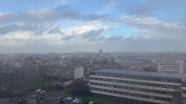 4K static shot of Bordeaux city skyline featuring Caserne Nansouty and Saint-Michel spire. Urban landscape with historic and modern architecture under a cloudy sky in France