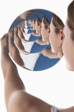 Woman holding a circular mirror creating a droste effect with her reflecting image