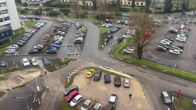 4K static shot of the Pellegrin University Hospital parking lot and medical buildings in Bordeaux, France. Urban healthcare infrastructure under a cloudy sky