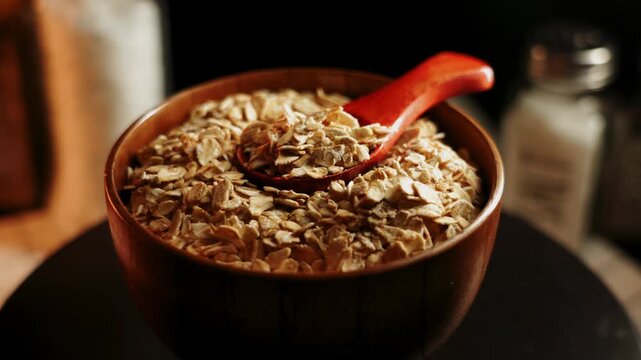 Making oatmeal in a wooden bowl with a red spoon at a kitchen table