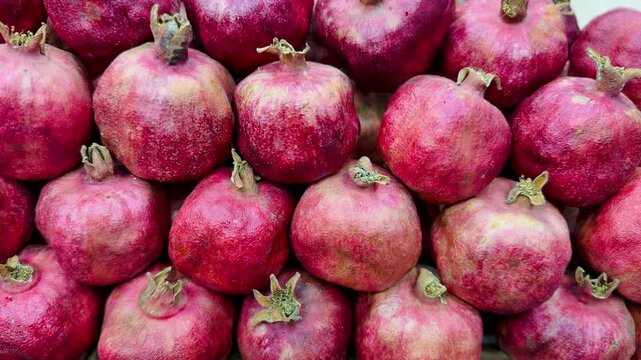 Ripe Red Pomegranates Stacked On Shelf In Grocery Display With Glossy Skins, Tight Closeup Showing Arils Promise, Seasonal Harvest Vibe, Abundant Arrangement For Sale, Retail Signage.