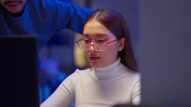 Asian programmers collaborating on software development at night, focused on writing code across multiple monitors in a tech office environment Programmers Collaborating on Software Development	