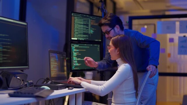 Asian programmers collaborating on software development at night, focused on writing code across multiple monitors in a tech office environment Programmers Collaborating on Software Development	