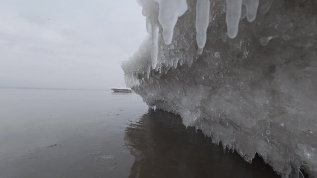 Ice formations hanging over cold water during winter thaw