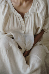 Close Up Woman Wearing White Linen Dress With Button Placket In Minimal Neutral Setting