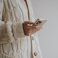 Woman Holding Phone Wearing Cream Cardigan