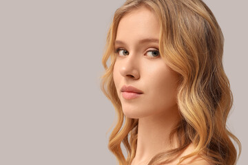 Naklejka premium Blonde young woman with curly hair on light background, closeup
