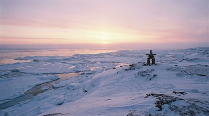 Inukshuk stands on snow-covered rocks above a frozen ocean with ice floes beneath a pastel pink and orange arctic sunset, serene tundra landscape evoking solitude and calm wilderness