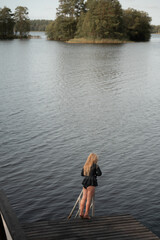 Fototapeta premium Girl standing on dock looking over calm lake 