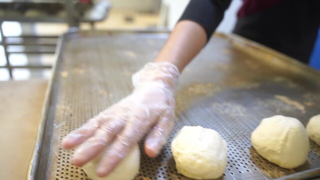 Qualified woman puts the dough on a baking sheet for making buns