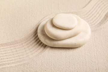 Composition with stack of spa stones and lines on sand as background, closeup. Zen concept