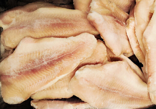 Frozen fish fillets in a supermarket or fishmonger shop. Seafood retail display and food storage concept. Vertical mobile photo. Concept seafood retail, food storage and wholesale fish distribution.