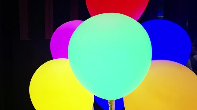 Cinematic zoom out shot revealing vibrant multicolored balloons with soft illumination.