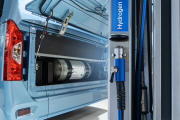 Hydrogen gas station and bus with an open hood and a hydrogen cylinder inside. Clean mobility concept