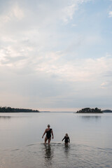Fototapeta premium Mother and child walking into lake at sunset 