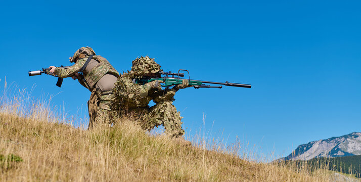 Two Military Snipers in Camouflage Ghillie Suits and Tactical Gear Training With Precision Rifle on Hillside