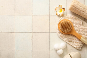 Massage brush with mitten, loofah and shower gel on white tile background