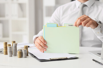 Fototapeta premium Businessman with folder at table in office, closeup. Tax concept
