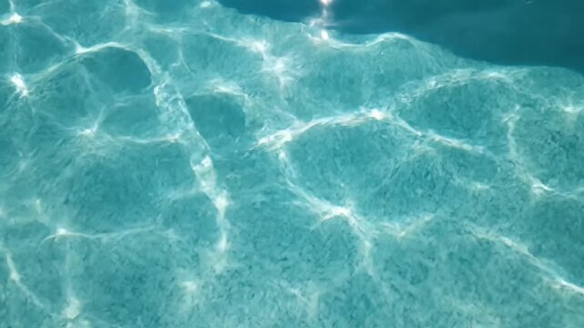 Close-up of bright sun reflecting on rippling clear turquoise pool water surface, concept for summer vacation poster, tropical resort brochure and relaxing background design