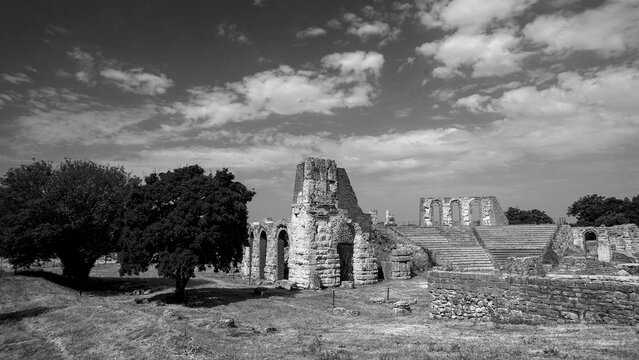 Archeologia in bianco e nero. Il Parco Archeologico del Teatro Romano di Gubbio con sullo sfondo la citt&agrave; medievale arroccata sulle colline, Umbria, Italia
