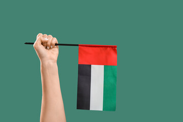 Female hand with UAE flag on green background