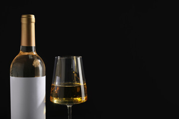 Bottle of wine with blank label and glass on black background