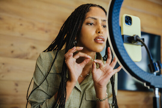 Female creator filming content with smartphone and ring light