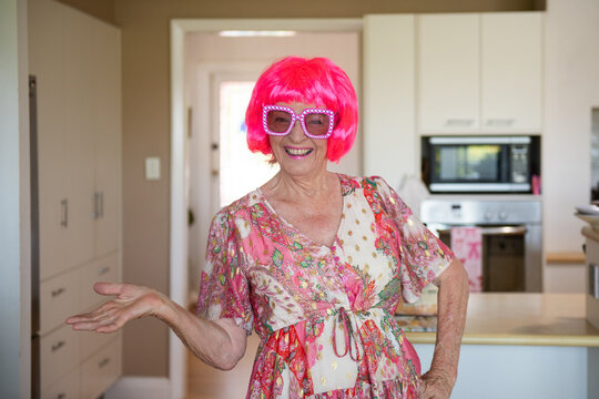 happy older woman wearing a fun pink wig and glasses