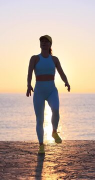 Fit woman performs stretching exercises at the beach during summer vacation. Slow motion