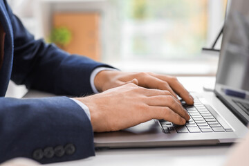Businessman working with laptop at table in office, closeup