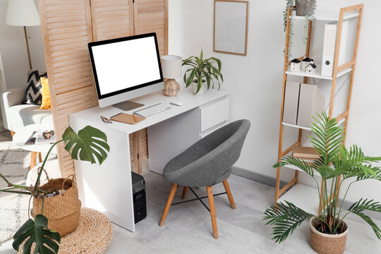 Interior of office with workplace, folding screen and plants