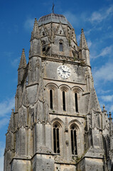 Obraz premium Main facade and ornate bell tower of the Basilica of Saint-Eutrope in Saintes, France. The historic Romanesque and Gothic architecture features a large clock and intricate stone carvings under a blue 