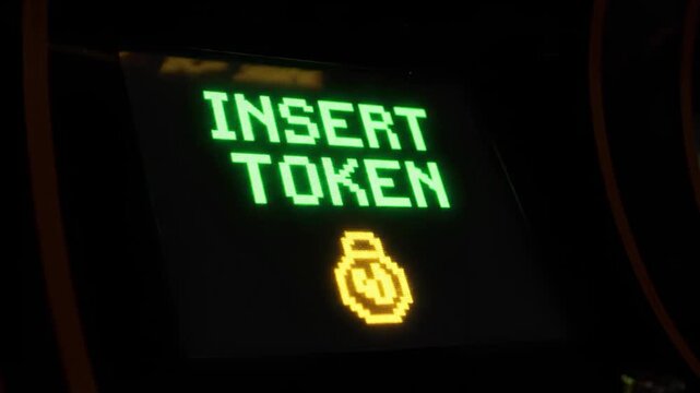 A dimly lit, close-up shot of an arcade game screen displaying "INSERT TOKEN". This image evokes nostalgia and could be used to represent gaming cultu